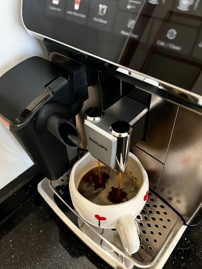 Close-up of coffee brewing in cup using modern espresso machine.