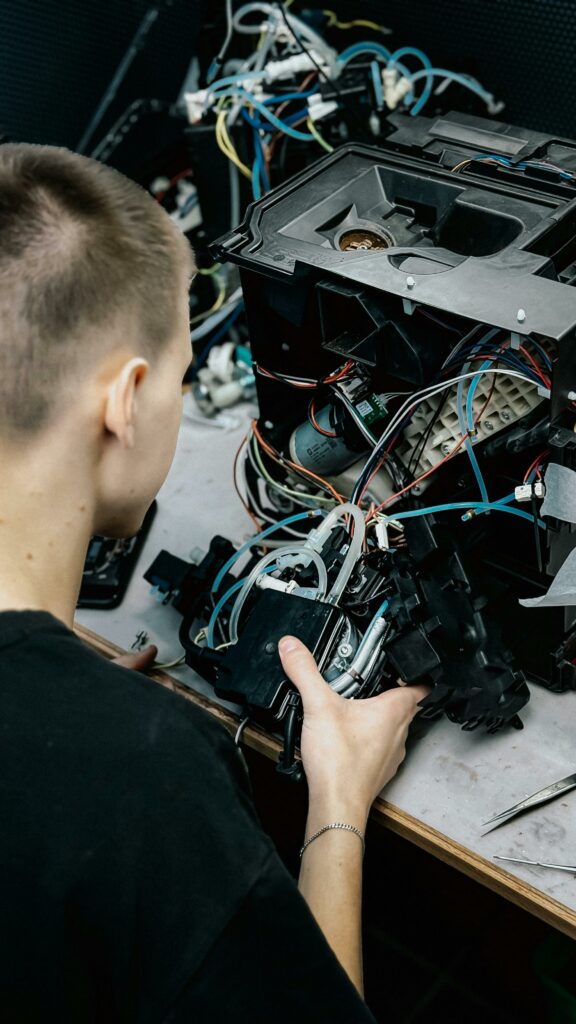 A technician carefully repairs an intricate electronic device, showcasing wires and components.