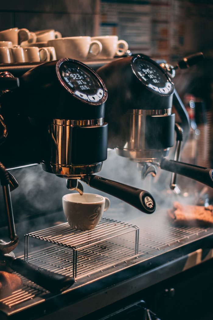 Close-up of a coffee machine pouring espresso into cups with steam rising, in a Romanian café.