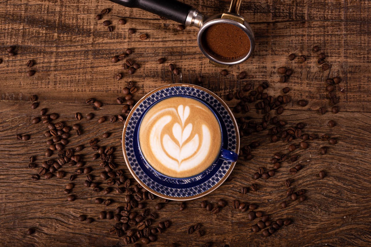 Overhead shot of a latte with frothy art in a blue ceramic cup on a rustic wooden table.